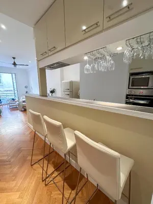 a kitchen with a bar with white chairs at Les Terrasses D'Herold in Nice