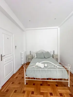 a white bedroom with a bed and a wooden floor at Les Terrasses D'Herold in Nice