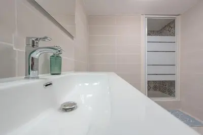 a white bathroom with a sink and a shower at Charmant 2 pièces au cœur de St Jean Cap Ferrat in Saint-Jean-Cap-Ferrat