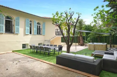 a patio with a table and chairs in a yard at VILLA DES PERGOLAS -6 Bdrs - 5 bathrs -Parking -Jardin -JACUZZI -TRAMstation , 10 min beach in Nice