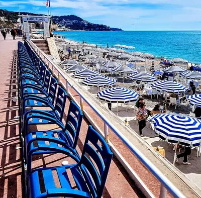 a row of blue chairs and umbrellas on a beach at Paradise Studio - Hyper Centre in Nice