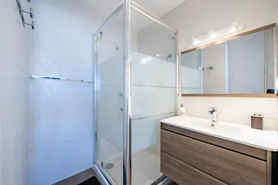 a bathroom with a sink and a glass shower at Appartement à 100m de la plage, climatisé in Cagnes-sur-Mer
