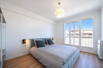 a bedroom with a large bed and a large window at Appartement à 100m de la plage, climatisé in Cagnes-sur-Mer