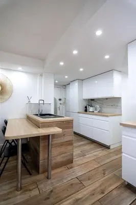 a kitchen with white cabinets and a wooden table at Bel appartement - Nice centre in Nice