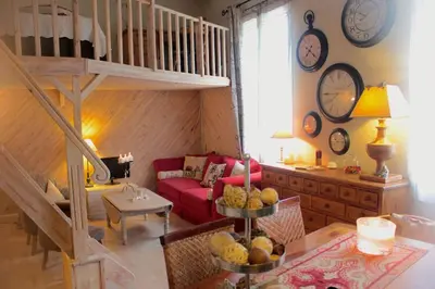 a living room with a red couch and clocks on the wall at Charming apartment in Beaulieu sur Mer in Beaulieu-sur-Mer