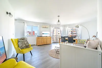 a living room with a yellow chair and a dining room at Confortable 2 pièces 54 m2 proche de la mer in Nice