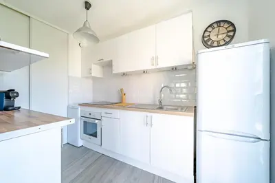 a kitchen with white cabinets and a clock on the wall at Confortable 2 pièces 54 m2 proche de la mer in Nice