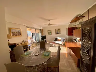 a living room with a glass table and a kitchen at 2P Cagnes Sur Mer- Proximité Plage, Parking in Cagnes-sur-Mer