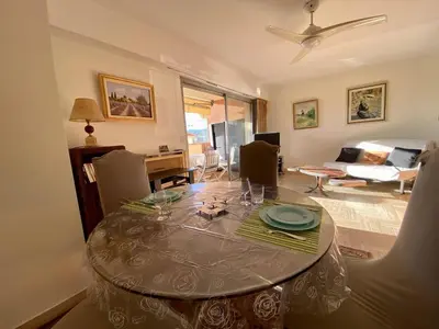 a dining room with a table and a living room at 2P Cagnes Sur Mer- Proximité Plage, Parking in Cagnes-sur-Mer