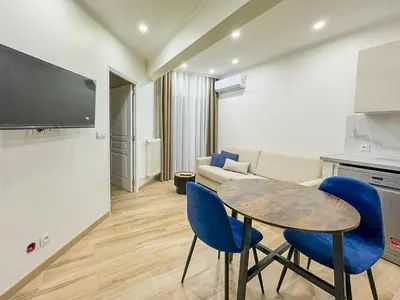 a living room with a table and blue chairs at Gare Du Sud - Wifi, AC, balcon in Nice