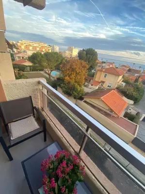 a balcony with a bench and a table and flowers at Sea View Apartment - Private Parking, Swimming Pool, Air Conditioning in Cagnes-sur-Mer