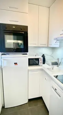 a kitchen with white cabinets and a microwave at Sea View Apartment - Private Parking, Swimming Pool, Air Conditioning in Cagnes-sur-Mer