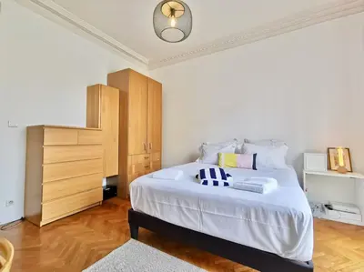 a bedroom with a large white bed and a wooden cabinet at Appartement Nice Bellecour in Nice