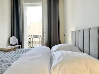 a bedroom with a bed with white pillows and a window at Bright, newly renovated apartment in Nice