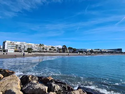 a beach with rocks in the water and buildings at Studio cosy front de mer à 5min de Nice in Saint-Laurent-du-Var