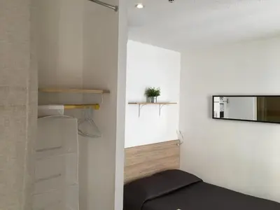 a small bedroom with a mirror on the wall at Hôtel du Petit Louvre in Nice