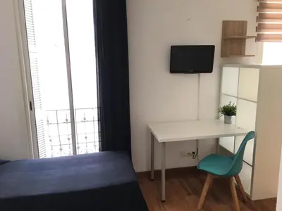 a small room with a desk and a bed and a tv at Hôtel du Petit Louvre in Nice