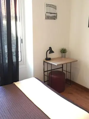 a bedroom with a bed and a desk with a lamp at Hôtel du Petit Louvre in Nice