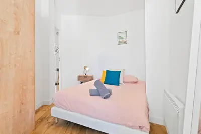 a bedroom with a bed with pink sheets and blue pillows at Terrasse des Oliviers in Nice