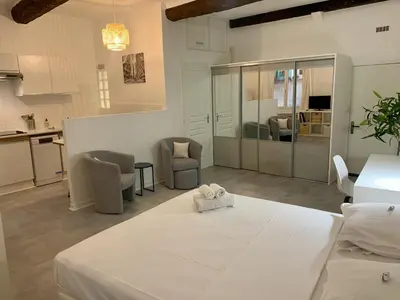 a room with a bed and chairs and a kitchen at ApartHotel Riviera - Cocon de Gilly - Old Town Promenade des Anglais in Nice