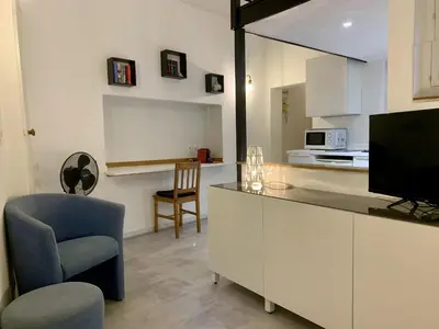 a living room with a kitchen with a tv and a chair at ApartHotel Riviera - DUPLEX DE JULES - Large Studio with A C - Old Town Promenade des An in Nice