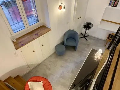 an empty room with a blue chair and a window at ApartHotel Riviera - DUPLEX DE JULES - Large Studio with A C - Old Town Promenade des An in Nice