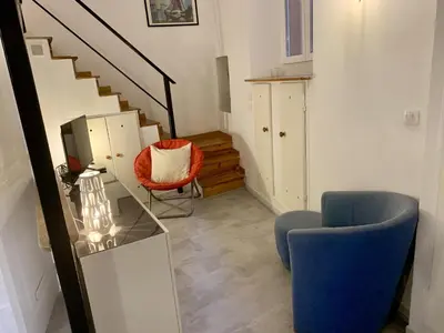 a living room with a blue chair and a television at ApartHotel Riviera - DUPLEX DE JULES - Large Studio with A C - Old Town Promenade des An in Nice
