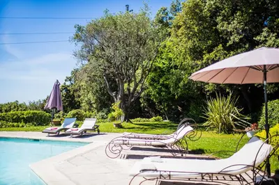 a group of chairs and an umbrella next to a pool at LOU MAS SOUBRAN VI2083 by RIVIERA HOLIDAY HOMES in Nice