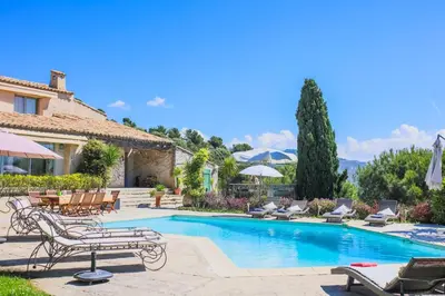 a pool with chairs and umbrellas and a house at LOU MAS SOUBRAN VI2083 by RIVIERA HOLIDAY HOMES in Nice