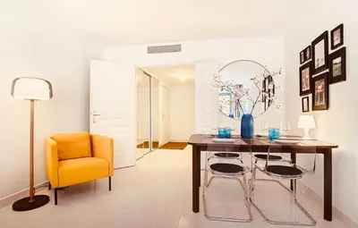 a dining room with a table and a yellow chair at Appartement Nice Palais de la Méditerranée in Nice