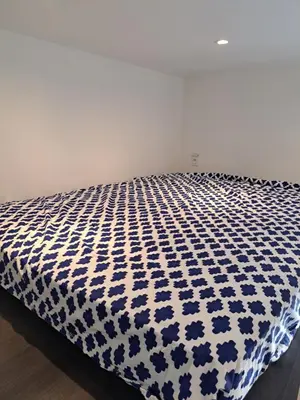 a bed with a blue and white comforter on it at Studio coin nuit terrasse à 5 minutes de la plage N1 in Saint-Laurent-du-Var