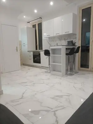 a kitchen with white cabinets and a marble floor at Appartement confortable a proximite de la mer. in Nice