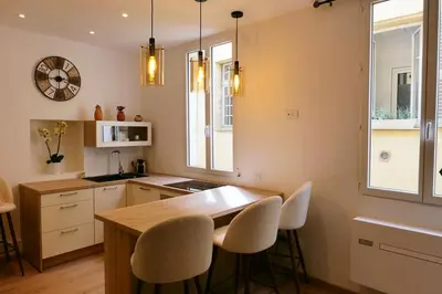 a kitchen with a wooden table and white chairs at Cocooning Atmosphère old Nice in Nice