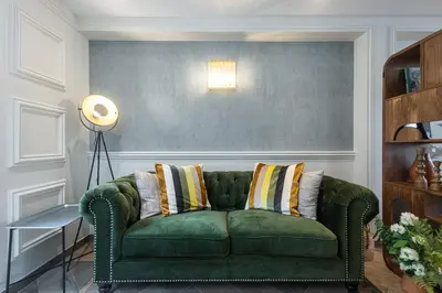 a green couch with striped pillows in a living room at Villa fleurie in Cagnes-sur-Mer
