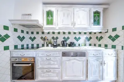 a kitchen with white cabinets and green and white tiles at Appartement en plein coeur de Cagnes sur Mer in Cagnes-sur-Mer
