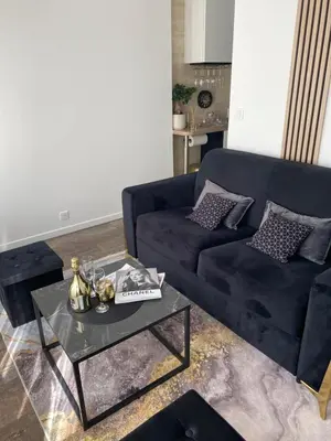 a living room with a black couch and a table at Denis&kanya in Nice