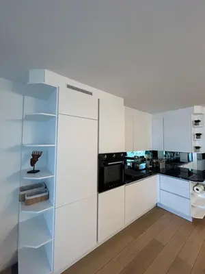 a kitchen with white cabinets and black appliances at Sunny Days in Nice