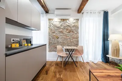 a kitchen with a table and chairs and a stone wall at Pretty & Quiet Studio in Port Area in Nice