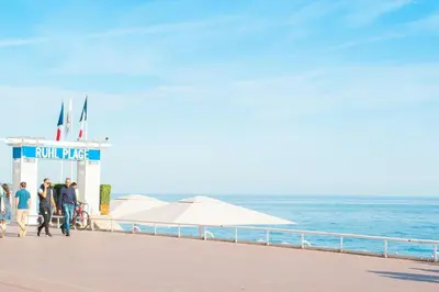 a group of people walking on a boardwalk next to the ocean at 50 meters from the beach ! Best location in Nice in Nice