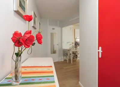 a vase with red flowers on a table in a room at Blue Lagon Five Stars Holiday House in Nice