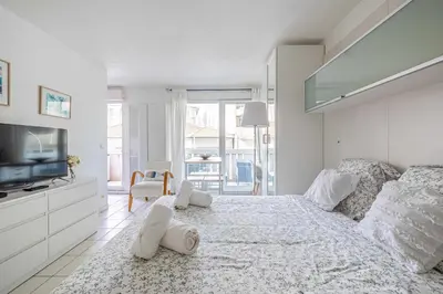 a white bedroom with a large bed and a tv at Charming Studio with pool & balcony -Heart of Nice in Nice