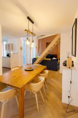 a dining room and living room with a wooden table and chairs at Le Grand Ruisseau in Nice