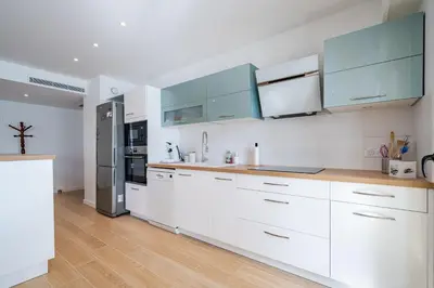 a kitchen with white cabinets and a refrigerator at Magnifique T2, parking, face mer in Cagnes-sur-Mer
