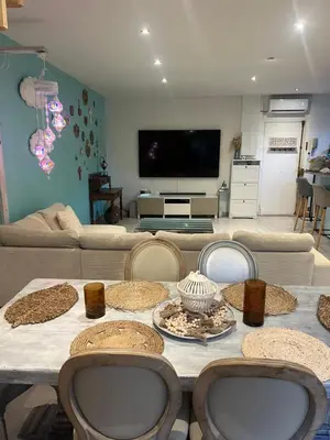 a living room with a table with chairs and a tv at Duplex quatre pièces - une chambre bébé à 5 minutes de la plage in Nice