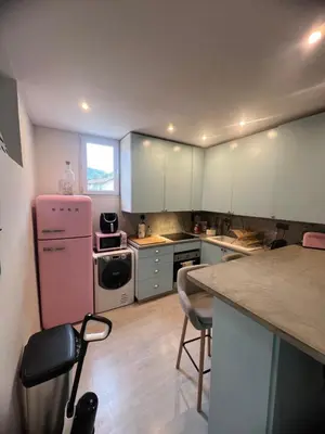a kitchen with white cabinets and a pink refrigerator at Duplex quatre pièces - une chambre bébé à 5 minutes de la plage in Nice