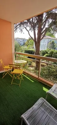 a balcony with a table and chairs and a tree at 2 pièces au calme avec terrasse et climatisation in Nice