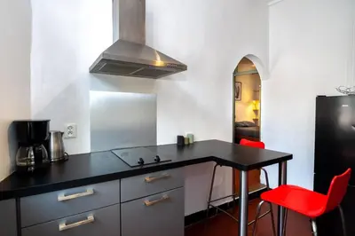 a kitchen with a black counter and red chairs at Magnifique 2p au coeur du vieux Nice in Nice