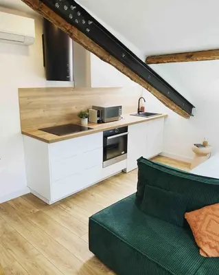 a kitchen with white cabinets and a green couch at Beautiful refurbished cozy apartment in Nice