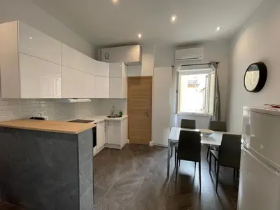 a kitchen with white cabinets and a table and chairs at Massena : Hyper Centre Studio 2p in Nice