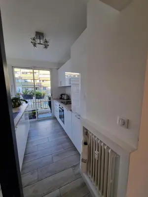a kitchen with white cabinets and a wooden floor at Magnifique T3, spacieux, lumineux et traversant in Nice